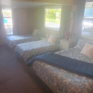 1 dormitorio con 2 camas y 2 ventanas en Daydream house, Sunrise, sunset views across lake en Rotorua