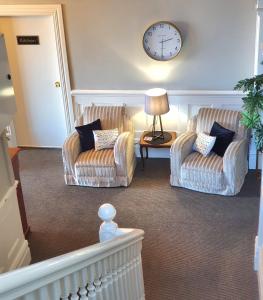 un soggiorno con due sedie e un orologio sul muro di Work Stay at 123 a Dunedin