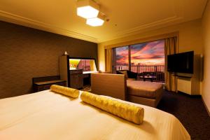 宜野湾市にあるラグナガーデンホテルのベッドとリビングルームが備わるホテルルームです。