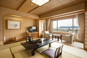 a living room with a table and a large window at Takuboku Tei in Hakodate