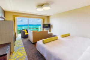 宜野湾市にあるラグナガーデンホテルのベッド付きのホテルルームで、海の景色を望めます。