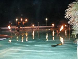 dos personas de pie en una piscina por la noche en Villaggio Hotel Agrumeto, en Capo Vaticano