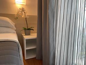 a bedroom with a bed and a window with a plant at Hotel Augustus in Milano Marittima