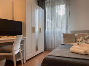 a bedroom with a bed and a desk with a television at Hotel Augustus in Milano Marittima