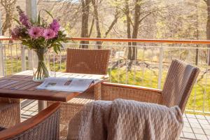 - une table en bois avec un vase de fleurs sur une terrasse couverte dans l'établissement HIDDENSEE I mit Ostseeblick Haus Fore, à Lohme