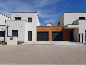 a house with two garage doors in a driveway at Le GREEN'SPA - DIJON - SPA-jardin-parking privé in Longvic