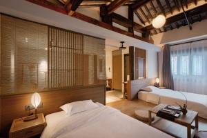 a bedroom with two beds and a table with two lamps at Uin Oriental Hotel in Wuxi