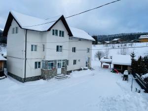 a large white house with snow on the ground at Casa Korina in Azuga