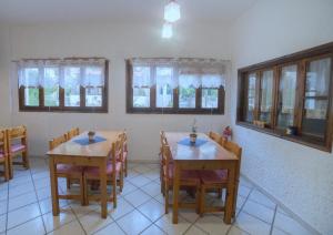 a dining room with two tables and chairs and windows at Oinoi Hotel in Agios Kirykos +18 photos