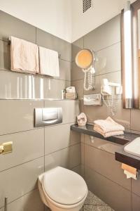 ein Badezimmer mit einem WC, einem Waschbecken und einem Spiegel in der Unterkunft Hotel Haus Berlin in Bonn