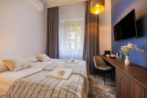 a bedroom with a bed and a desk and a television at Aparthotel Cracovia Residence in Krakow