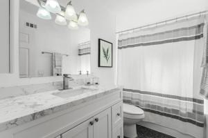 a white bathroom with a sink and a toilet at Modern 4 King Beds, Beautiful Large Backyard, Golf, WFH, Long Stays, WI-FI, FWY, 25 mins to Beach in Casa Conejo