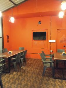 a dining room with tables and chairs and a tv on a wall at Leo's Residency Coorg in Kushālnagar