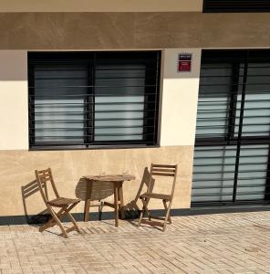 2 sillas y una mesa de madera frente a un edificio en Loft Miramar en Fuengirola