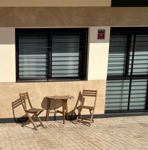two chairs and a wooden table in front of a building at Loft Miramar in Fuengirola
