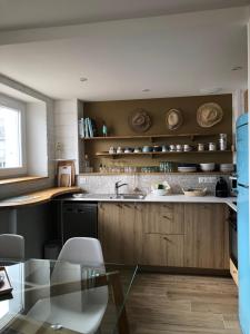 a kitchen with wooden cabinets and a glass table at Face à la mer, bel appartement in Saint-Nazaire