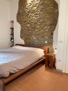 1 dormitorio con cama y pared de piedra en Rododendro casa sulle colline Toscane vicino San Giminiano en Castelfalfi