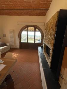 a living room with a stone fireplace with a door at Rododendro casa sulle colline Toscane vicino San Giminiano in Montaione