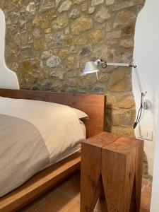 1 dormitorio con una pared de piedra, 1 cama y 1 lámpara en Rododendro casa sulle colline Toscane vicino San Giminiano en Castelfalfi