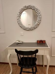 a desk with a mirror and a black chair at Cameron Lovely Cottage 3 Rooms in Tanah Rata