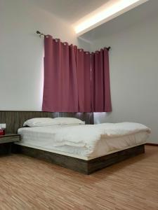 a bedroom with two beds and a purple curtain at Cameron Lovely Cottage 3 Rooms in Tanah Rata