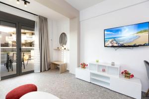 a white living room with a tv on a wall at TwinStars Superior Apartment in Gerakini