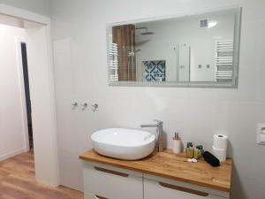 a white bathroom with a sink and a mirror at Apartament Zimowiec in Duszniki Zdrój