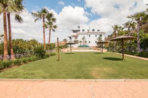 カサーレスにある2207-Modern apt with terrace and amazing seaviewのヤシの木と傘付きの芝生があるリゾート