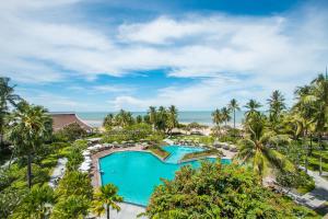 uma vista aérea de uma piscina de resort com palmeiras e do oceano em The Regent Cha Am Beach Resort, Hua Hin em Cha Am