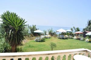 a garden with tables and chairs and umbrellas at SUNSET BAY STUDIOS in Agios Georgios