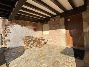 un patio con mesa y sillas en una pared de piedra en la casita de oruña, en Oruña