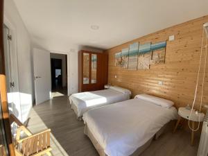 a bedroom with two beds and a wooden wall at la casita de oruña in Oruña