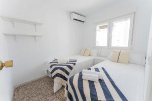 Precioso apartamento en altura في Altura: غرفة بيضاء بسريرين واريكة