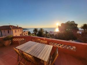 a wooden table and chairs on a balcony with the sunset at Villa lours in Le Trayas