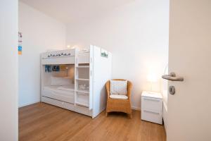 a small white room with a bed and a chair at Villa Anna -Whg 09 in Ahlbeck