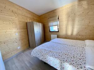 1 dormitorio con 1 cama y pared de madera en la casita del puente viejo, en Oruña