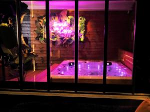 a jacuzzi tub in a room with purple lighting at SXCAPE ROOM in Aigues-Mortes