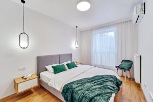 um quarto com uma cama com lençóis verdes e uma cadeira em ApartFonte - Mickiewicza 2A - garaż podziemny em Polanica-Zdrój