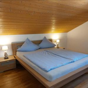 a bed with blue sheets and two pillows on it at Ferienwohnung Holzmaier in Bad Aibling