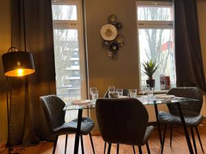 een eetkamer met een tafel, stoelen en ramen bij AKK6 Designpartment nähe Hbf Uni Oper in Maagdenburg
