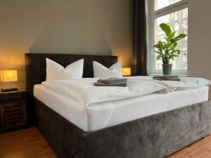 een groot bed met witte lakens en een plant erop bij AKK6 Designpartment nähe Hbf Uni Oper in Maagdenburg