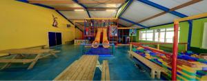 Chalet Op Bosrijk Familiepark في رالته: غرفة لعب مع ملعب مع زحليقة