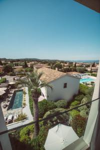 uma vista a partir da varanda de uma casa com piscina e palmeiras em Hotel le Mandala em Saint-Tropez