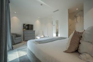 een slaapkamer met een groot wit bed en een stoel bij Hotel le Mandala in Saint-Tropez