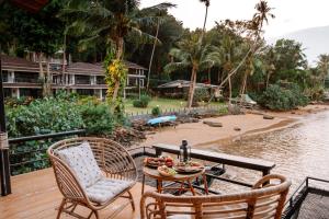 a table and chairs on a deck next to a body of water at Resolution Resort in Ko Chang