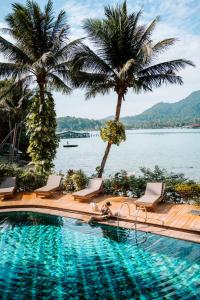 a swimming pool with palm trees and a body of water at Resolution Resort in Ko Chang +126 photos