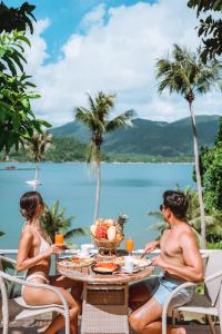 a man and a woman sitting at a table with a bowl of fruit at Resolution Resort in Ko Chang