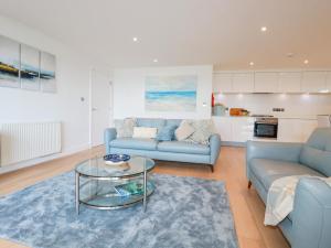 a living room with two blue couches and a glass table at Fistral Retreat in Newquay