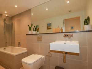 a bathroom with a sink and a toilet and a mirror at Fistral Retreat in Newquay +31 photos