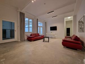 a living room with two red couches and a tv at RAJ Living - 300m2 Loft with 7 Rooms - 15 Min Messe DUS & Old Town DUS in Düsseldorf